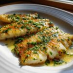 Three fillets of perfectly Pan-Seared Flounder Brown Butter Lemon glistening in sauce and topped with fresh parsley.