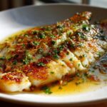 A close-up of a perfectly Pan-Seared Flounder Brown Butter Lemon served in a white dish with rich sauce.