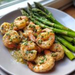 Close-up of Sheet Pan Crispy Garlic Butter Shrimp and Asparagus served on a light gray plate.