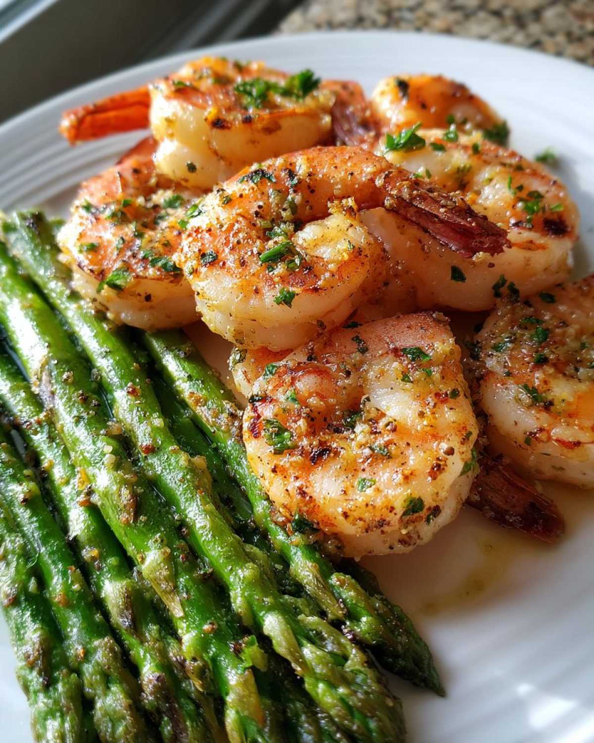 Close-up of perfectly cooked Sheet Pan Crispy Garlic Butter Shrimp and Asparagus on a white plate.