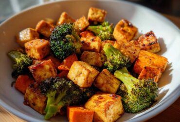 Close-up of crispy Sheet Pan Crispy Honey Mustard Tofu cubes mixed with roasted broccoli florets in a white bowl.
