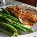 Flaky, glazed Sheet Pan Honey Mustard Salmon served next to bright green beans on a white plate.