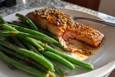 Flaky, glazed Sheet Pan Honey Mustard Salmon served next to bright green beans on a white plate.
