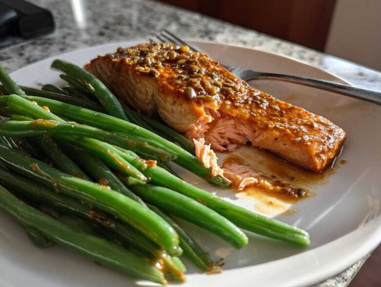 Flaky, glazed Sheet Pan Honey Mustard Salmon served next to bright green beans on a white plate.