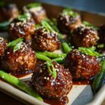 Close-up of glazed Sheet Pan Sticky Sesame Meatballs with snap peas and sesame seeds.