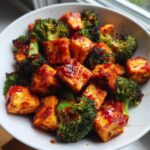 Close-up of crispy Sheet Pan Sweet Chili Tofu with Broccoli florets coated in a glossy red sauce.