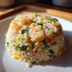 A perfectly molded serving of shrimp fried rice, featuring plump shrimp, scrambled egg, and green onions, showcasing the Gluten-Free Lemon Pepper Fried Rice.