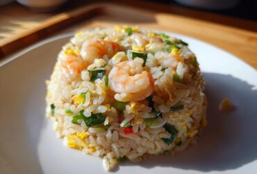 A perfectly molded serving of shrimp fried rice, featuring plump shrimp, scrambled egg, and green onions, showcasing the Gluten-Free Lemon Pepper Fried Rice.