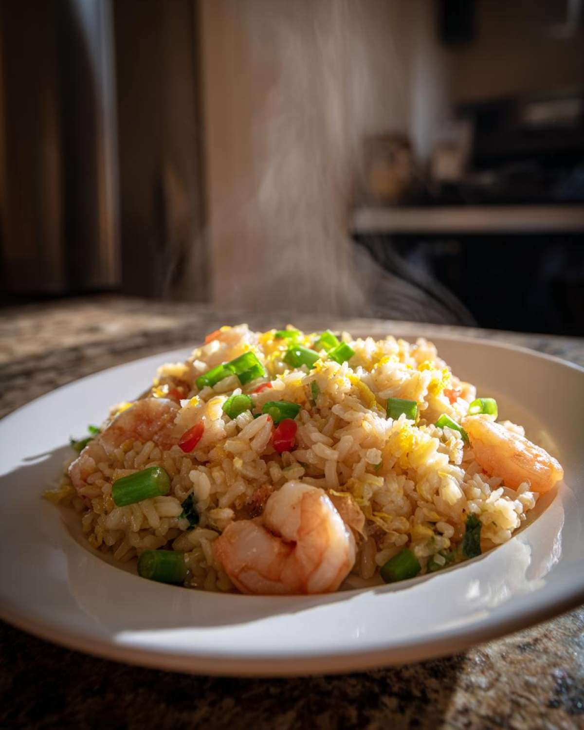 Close-up of hot, steaming Gluten-Free Lemon Pepper Fried Rice featuring shrimp, green onions, and red peppers on a white plate.