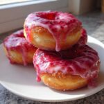 Close-up of three golden-brown Strawberry Donut Rolls stacked, covered in a thick, dripping pink strawberry glaze.