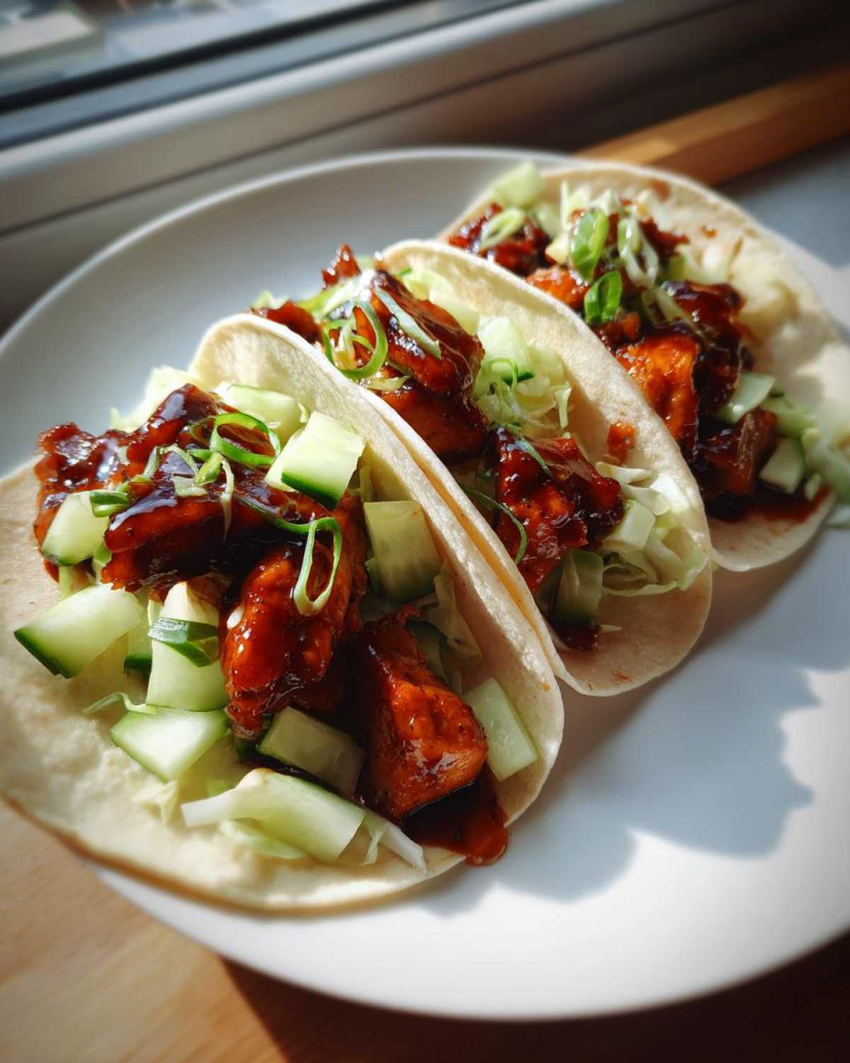 Three soft shell Teriyaki Chicken Tacos filled with glazed chicken, crisp cucumber, and green onions.
