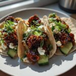 Three loaded Teriyaki Chicken Tacos featuring glazed chicken, creamy white cheese, sliced cucumbers, and green onions.