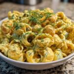 Close-up of Vegan Creamy Lemon Chickpea Pasta Salad with dill garnish in a white bowl.