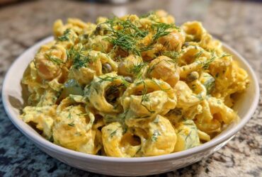 Close-up of Vegan Creamy Lemon Chickpea Pasta Salad with dill garnish in a white bowl.