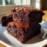 Close-up of stacked, fudgy Zero Sugar Brownies with Greek Yogurt, catching sunlight on a white plate.