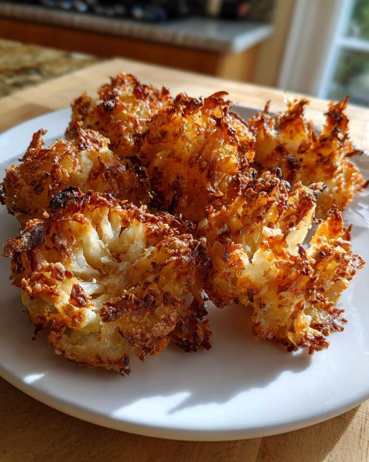 Close-up of several golden brown Air Fryer Crispy Mini Blooming Onions served on a white plate.