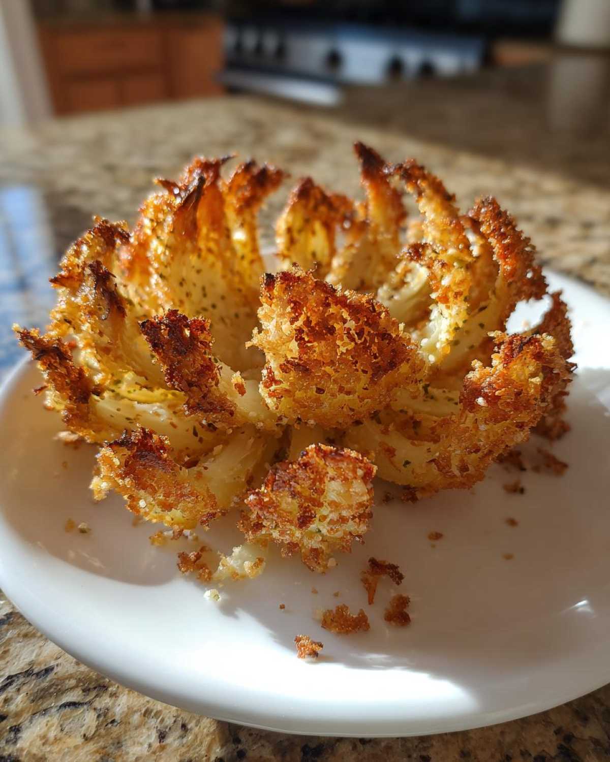 A single, perfectly cooked Air Fryer Crispy Mini Blooming Onions, golden brown and resting on a white plate.