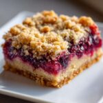 A single serving of berry crumble Dessert Squares showing a thick layer of dark purple berries and a crumbly topping.