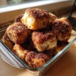 A close-up of fluffy Cinnamon Sugar Biscuit Bites piled high in a clear glass serving dish.