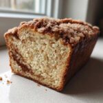 A close-up view of a freshly baked Cinnamon Sugar Donut Bread loaf with a visible cinnamon swirl and sugary topping.