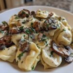 A close-up of rich Creamy Mushroom Tortellini Alfredo, generously coated in sauce and topped with sautéed mushrooms and parsley.