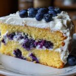 A delicious slice of Fluffy Lemon Blueberry Naked Cake with layers of yellow cake, blueberry filling, and whipped cream frosting.