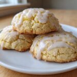 Close-up of three soft Lemon Ricotta Cookies stacked on a white plate, drizzled with lemon glaze and coarse sugar.