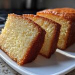 Close-up of three moist slices of golden pound cake served on a white plate.