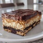 A thick, layered slice of Peanut Butter Chocolate Lasagna dessert on a white plate.