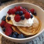 Close-up of Protein Pancake Bowls topped with yogurt, fresh raspberries, and blueberries.