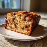 A close-up slice of moist Apple Cinnamon Bread showing rich cinnamon swirls and baked apple pieces.