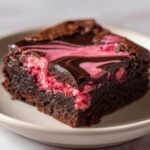 A single, rich square of Strawberry Brownies featuring a dark chocolate base and a vibrant pink, swirled strawberry cheesecake topping.