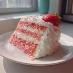 A perfect slice of layered Strawberry Cake with Cream Cheese Frosting, topped with a fresh strawberry.